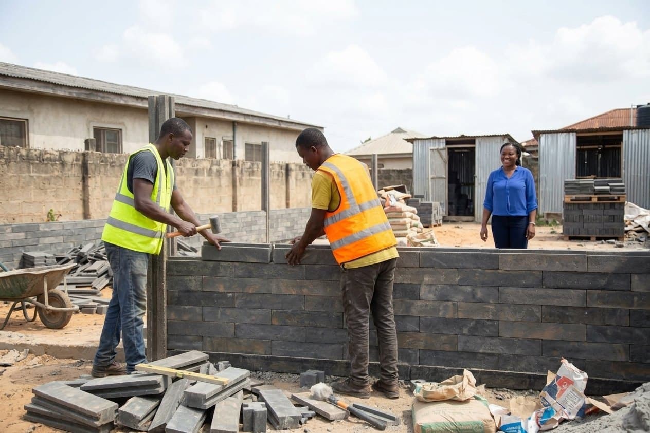 A crew laying interlocking recycled plastic blocks on a wall